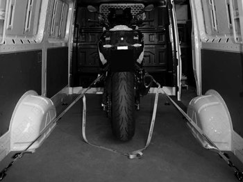 Moto sujeta con correas a los anclajes del suelo, vista desde las puertas traseras de la furgoneta